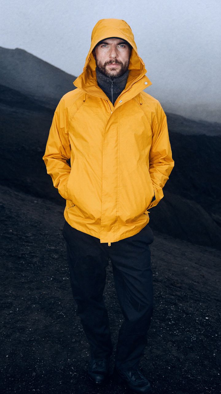 A man in a mustard technical jacket on a volcanic road