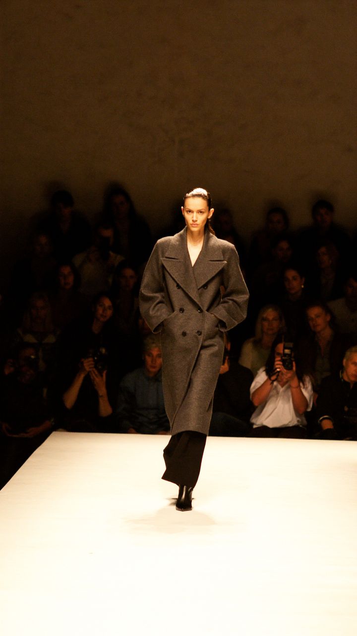 A model in a charcoal wool coat walking a runway