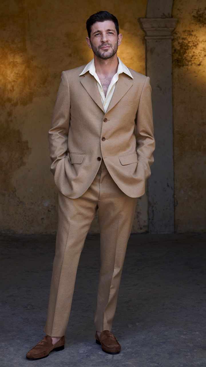 A man in a camel wool suit in a courtyard